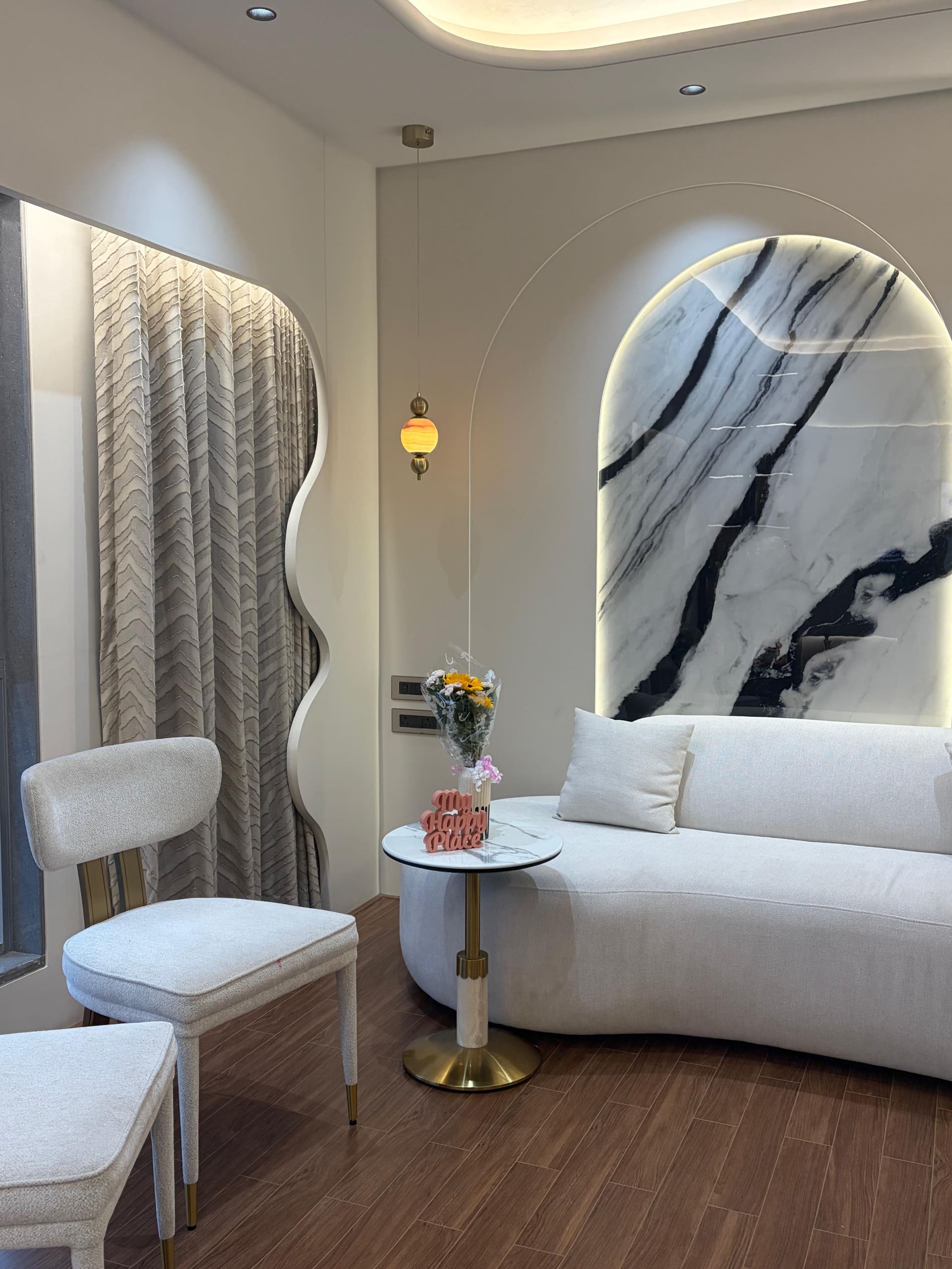 Asher Titan living room with curved sofa and marble feature wall